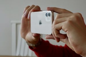 persona que sostiene un iPhone 12 con ambas manos para tomar una foto